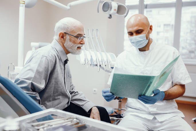An older man at the dental implant center is seeing if it's too late to get dental implants.
