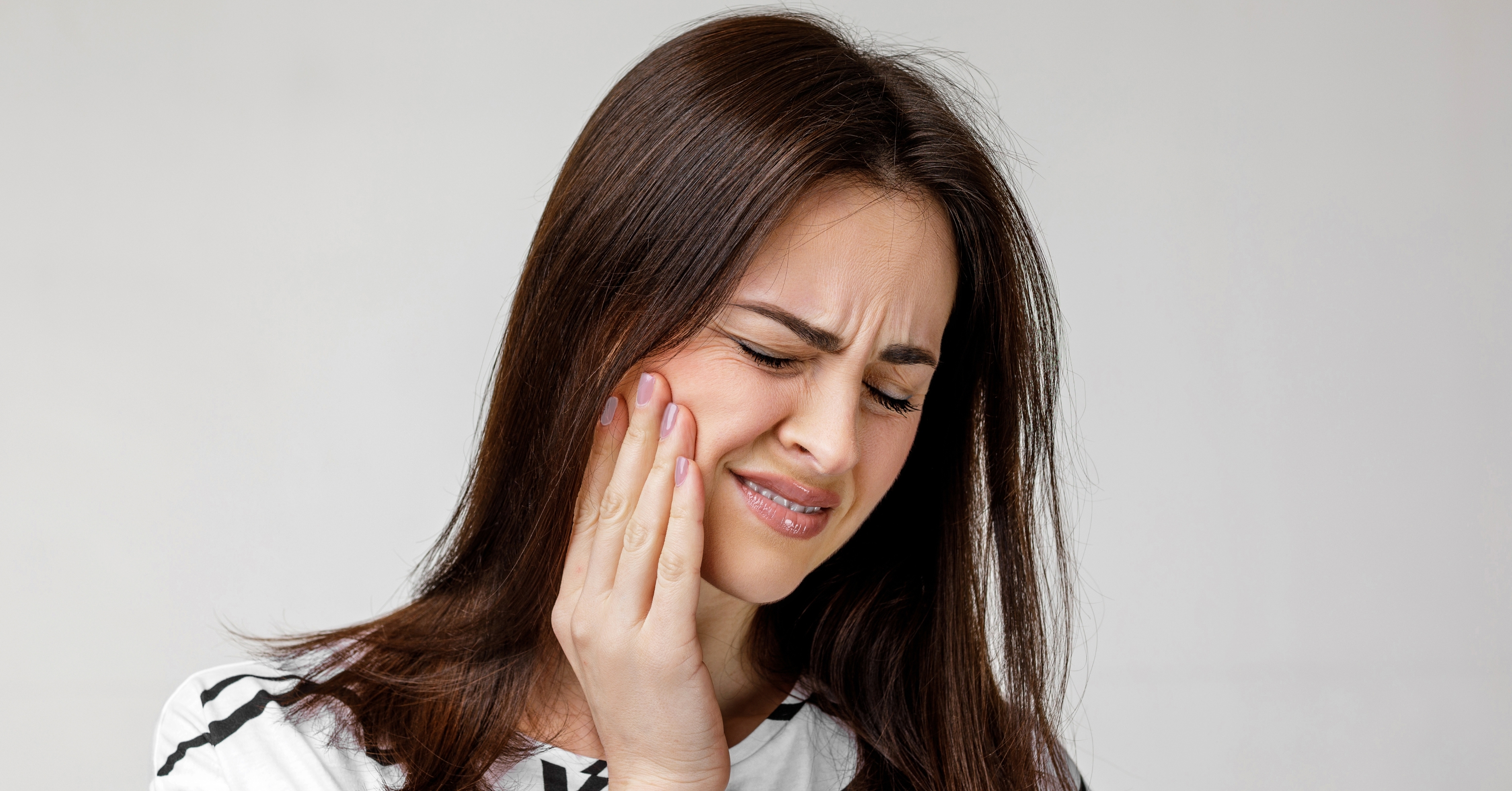 A woman touching cheek and jaw in pain