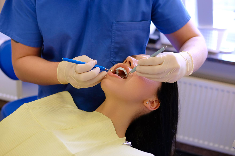 Dentist performing a dental checkup to examine teeth for cavities and determine if a filling is needed.