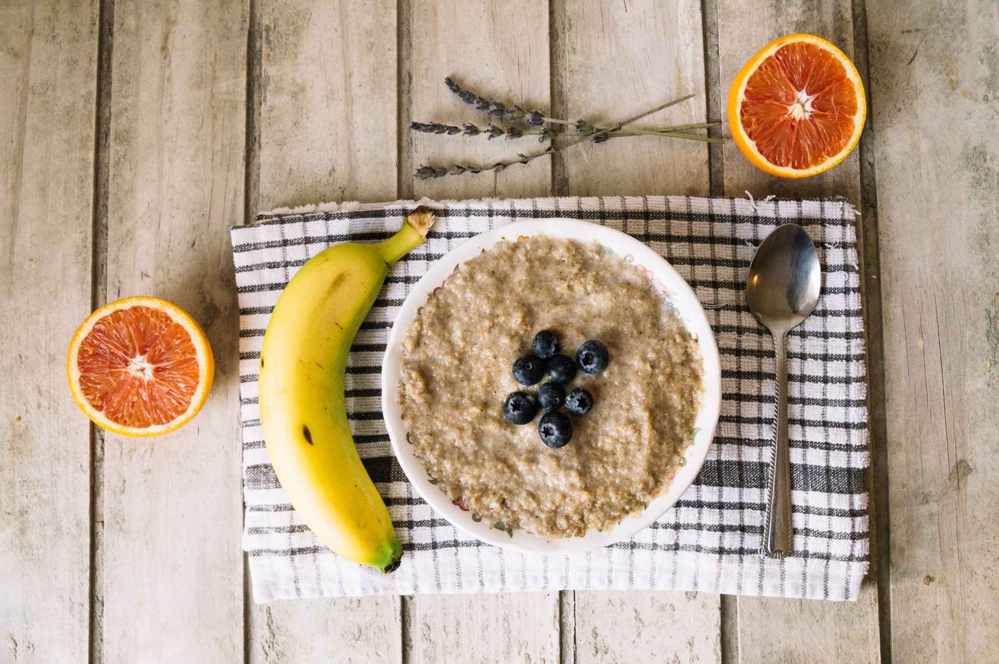 Bowl of oatmeal with banana and blueberries on a rustic table, a common soft food to eat after oral surgery.