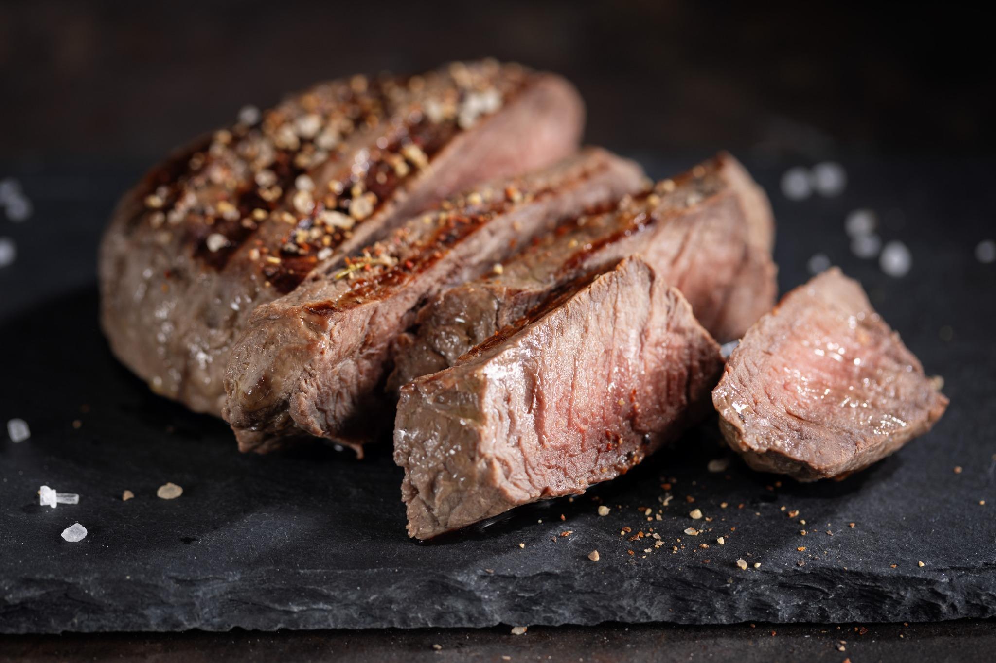 Close-up of tender, sliced beef seasoned with spices, an example of what foods not to eat after oral surgery.